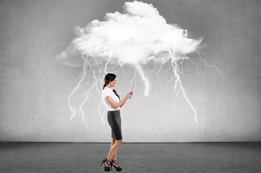 Businesswoman working on digital tablet in front of wall with thundercloud