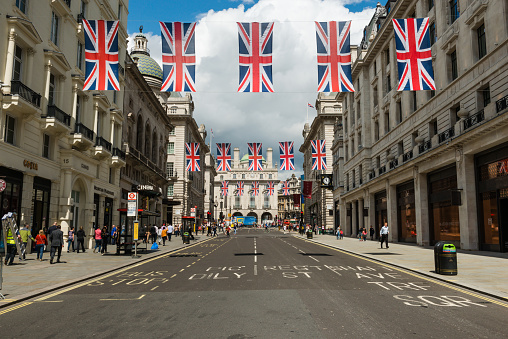 London, UK - June 23, 2016: The iconic Regent street flags with tourists and locals shopping in Piccadilly Circus late in the day.