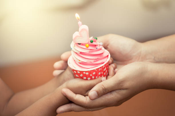 mother and child hand holding birthday cupcake in vintage color tone