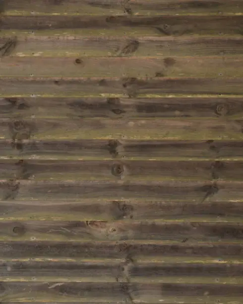 Horizontal running grungy brown stained and greened planks and boards from a waterfront cottage.
