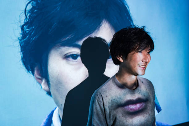 A mid adult man standing in a projected image of himself