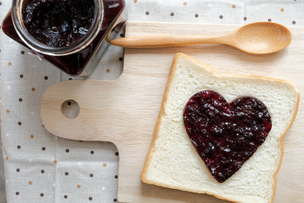 istock Toast with jam in shape of hearts on tablecloth background.  Top view 643848366