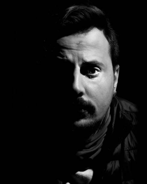 istock Black and white low-key man closeup portrait with black background 643848478