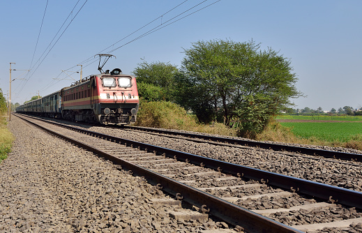 Indian long distance train passing near wheat field