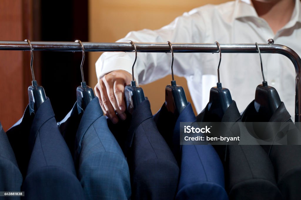 many suits on rack many suits hanging on rack with a man hand Coathanger Stock Photo