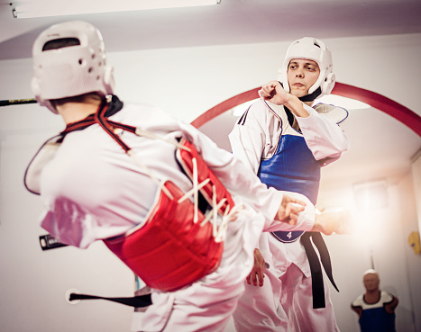 Taekwondo training in sport hall with tatami. Taekwondo is equally popular sport among girls and boys, young men and women. Sport develops physique and strength on lower and upper limbs equally. Professional taekwondo players practice with protective sportswear