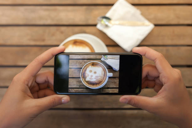 istock close-up hand holding phone taking coffee photo on table 643886986