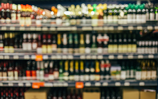 Blurred image of liquor wine bottles on shelf in supermarket.