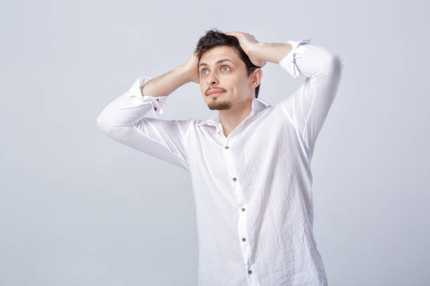 istock young attractive surprised brunette man in white shirt on gray b 643898144