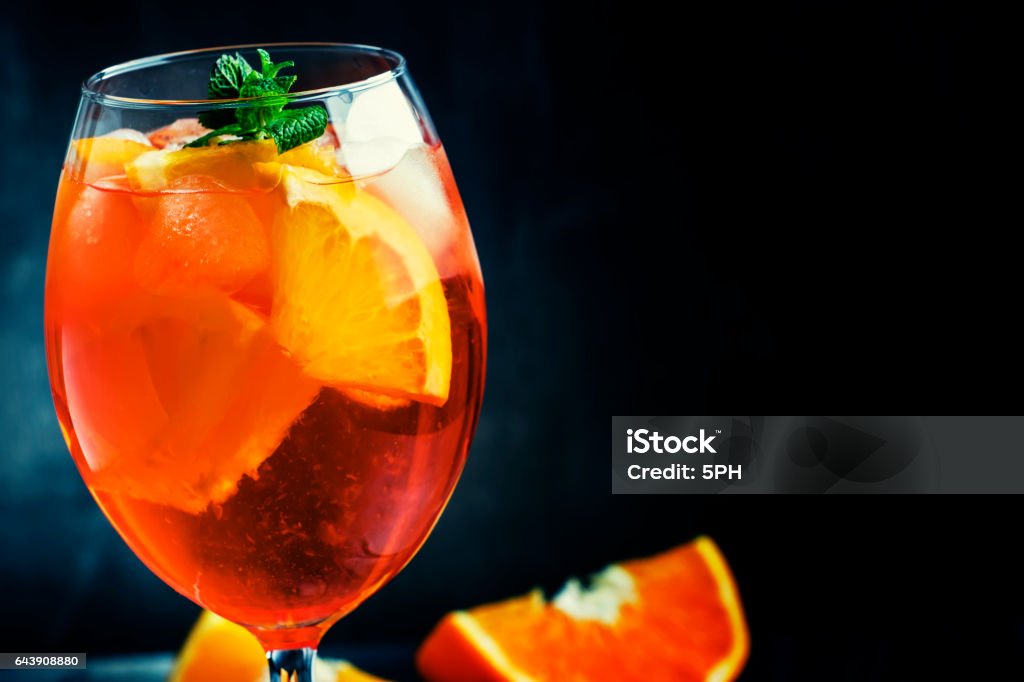 Summer cocktail aperitif with orange bitter, fruit, ice and soda Summer cocktail aperitif with orange bitter, fruit, ice and soda in tall glass, gray-silver background, selective focus Aperitif Stock Photo