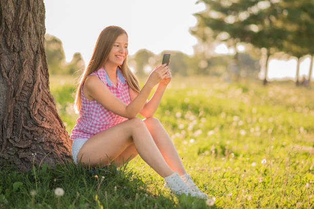 istock Happiness in Nature- Young woman sitting under tree 643912588