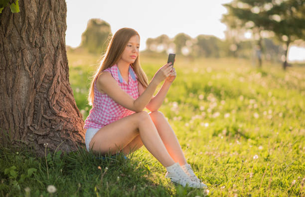 istock Happiness in Nature- Young woman sitting under tree 643913480
