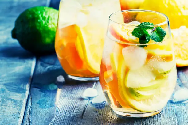 White sangria with fruit and ice, gray-silver background, selective focus