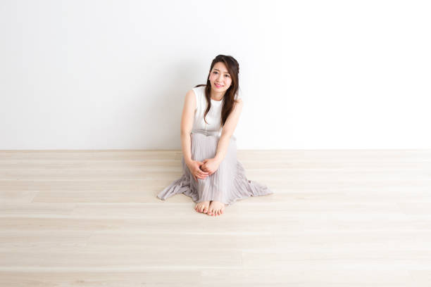 Portrait of beautiful young woman with dyed blue hair and a ponytail wearing a long sleeved crop top short jeans and high heels kneeling on a white background