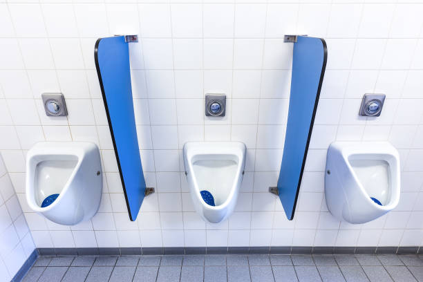 Urinals for boys on white wall with blue partitions in high school. Men and boys can use this sanitary facility when they have to urinate. It's easy to clean with all the tiles on the wall and on the floor. I took this photo in secondary school where I work.