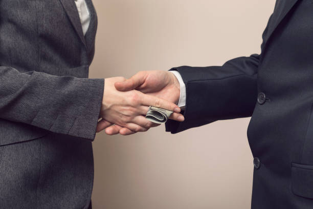 Business corruption Detail of two business people sealing the deal with bribe money. Selective focus corruption photos stock pictures, royalty-free photos & images