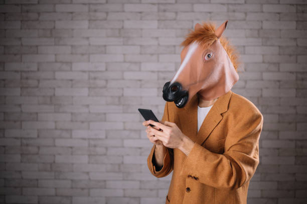 uomo con maschera da cavallo con cellulare - horse men animal head bizarre foto e immagini stock