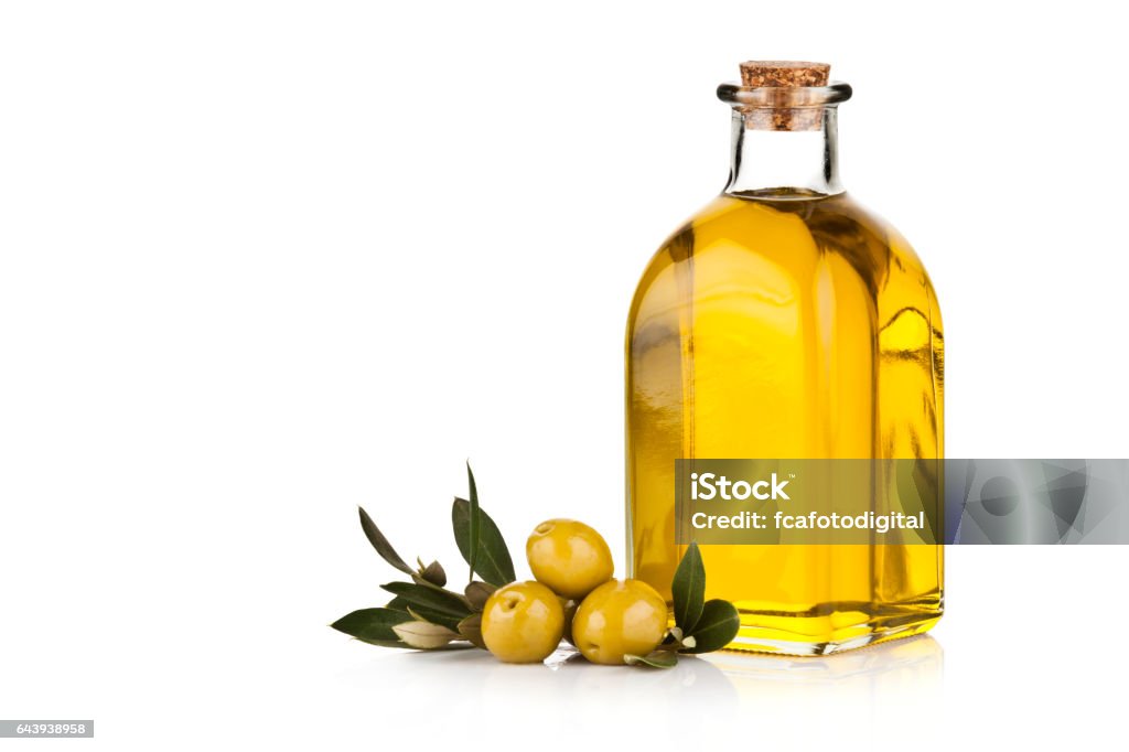 Olive oil bottle and green olives isolated on white background Horizontal shot of a single olive oil bottle and green olives with leaves isolated on white background. Copy space at the left side of the frame. DSRL studio photo taken with Canon EOS 5D Mk II and Canon EF 70-200mm f/2.8L IS II USM Telephoto Zoom Lens Olive Oil Stock Photo