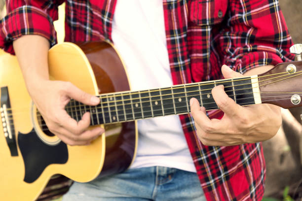 istock close up man is playing guitar while relaxing in public park 643943614