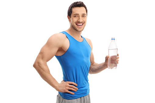 Athletic young man with a bottle of water smiling and looking at the camera isolated on white background