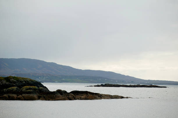 rocky coast line with calm grey sea and grey sky. Misty feeling