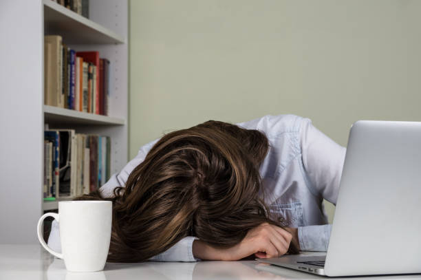 istock Tired girl resting her head on the table of working with computer 643969598