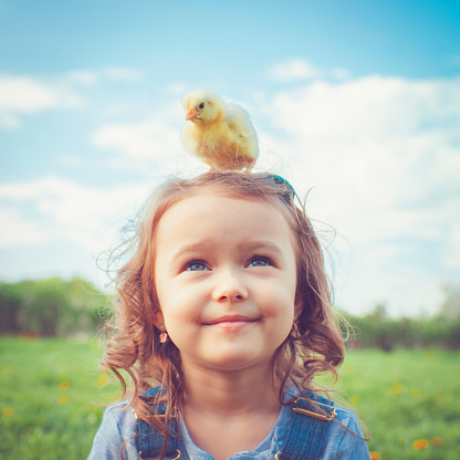 Little girl celebrating Easter outdoors with chicken