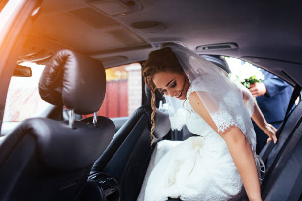 Happy bride and groom near car. Raindrops on wedding car.