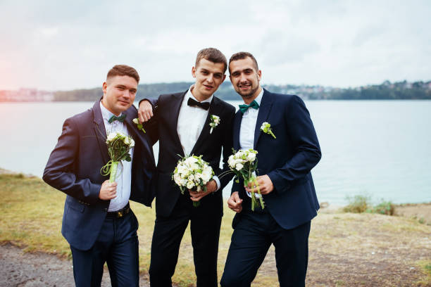 istock Confident smiling handsome groom in black suit with two groomsma 643981192