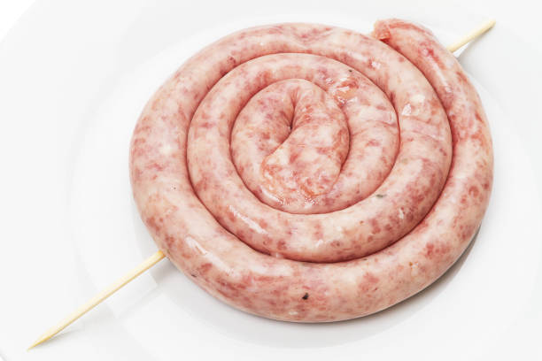 Top view of raw meat sausage ready to be grilled on a white plate