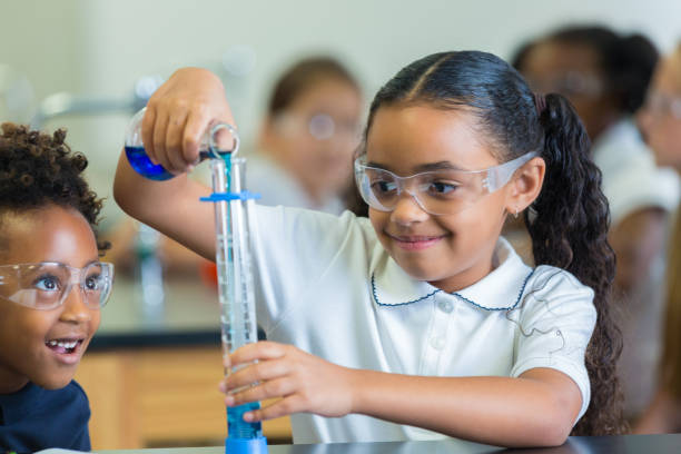istock Curious elementary schoolgirl participates in science experiment 643984434