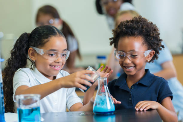 istock Elementary schoolgirl pours liquid into beaker 643984454