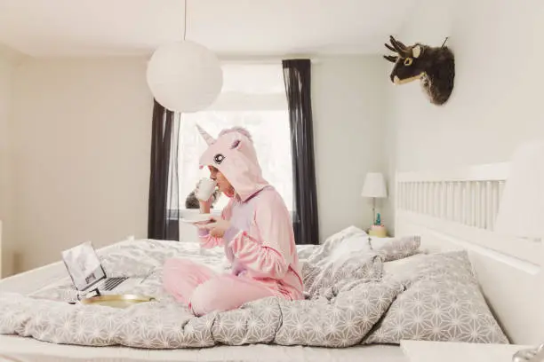 Photo of Playful woman in unicorn costume in bedroom