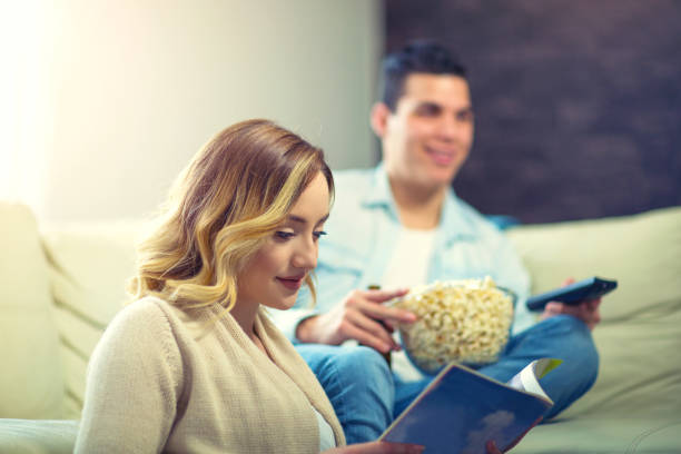 Man watching TV, woman reading magazine