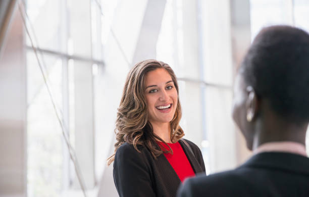 smiling corporate businesswomen talking - over the shoulder view fotos imagens e fotografias de stock