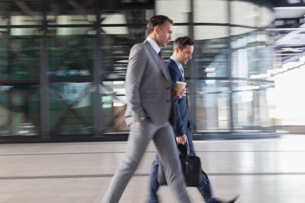 istock Corporate businessmen with coffee walking outside building 643999241