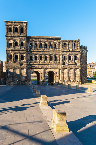 Trier, Germany - August 9th 2023: The entrance  of the back side of the Porta Nigra port city in Trier, Germany\n\nThe Porta Nigra (Latin for black gate), referred to by locals as Porta, is a large Roman city gate in Trier, Germany. It is a UNESCO World Heritage Site\nSource: Wikipedia