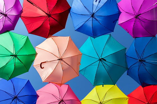 Bright, vibrant and colorful umbrellas or parasols in row pattern on blue sky background