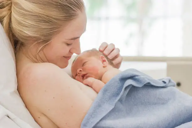 A mother holds her newborn in the hospital just after giving birth.