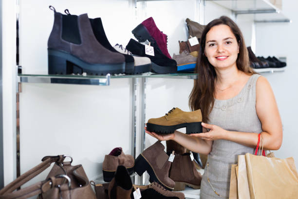 istock Young woman choosing fall boots in shoes store 644054920