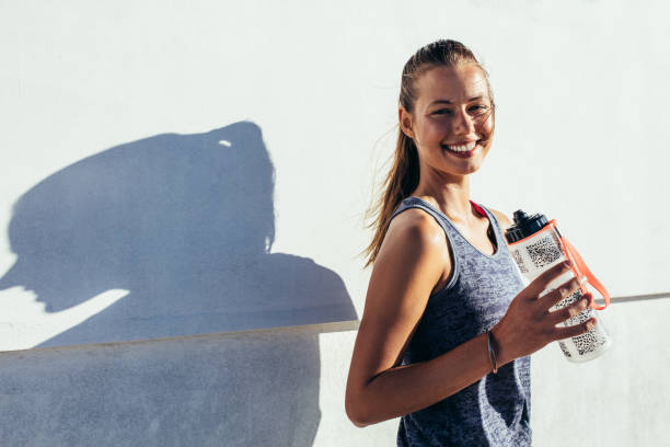 istock Happy female runner holding water bottle and smiling 644057962