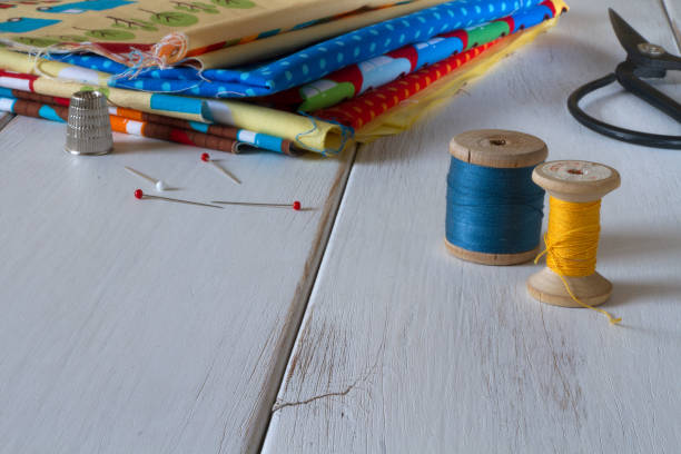 istock Colorful fabrics with vintage scissors, pins, measuring tape and rolling cotton threads on white wooden table 644060360