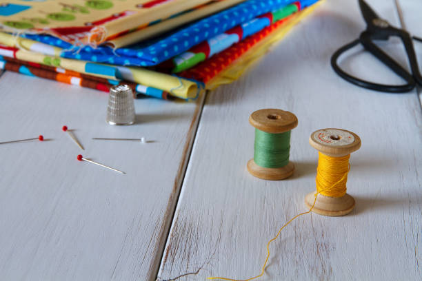 istock Colorful fabrics with vintage scissors, pins, measuring tape and rolling cotton threads on white wooden table 644060598