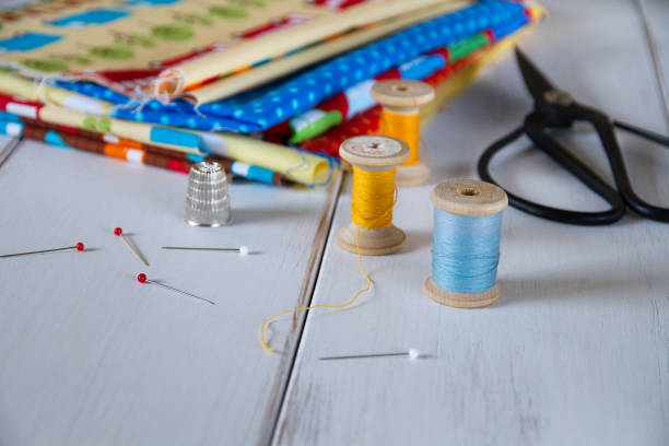 istock Colorful fabrics with vintage scissors, pins, measuring tape and rolling cotton threads on white wooden table 644060874