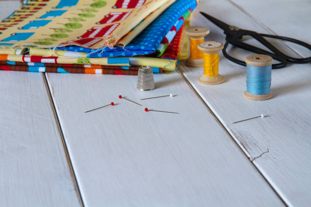 istock Colorful fabrics with vintage scissors, pins, measuring tape and rolling cotton threads on white wooden table 644061284