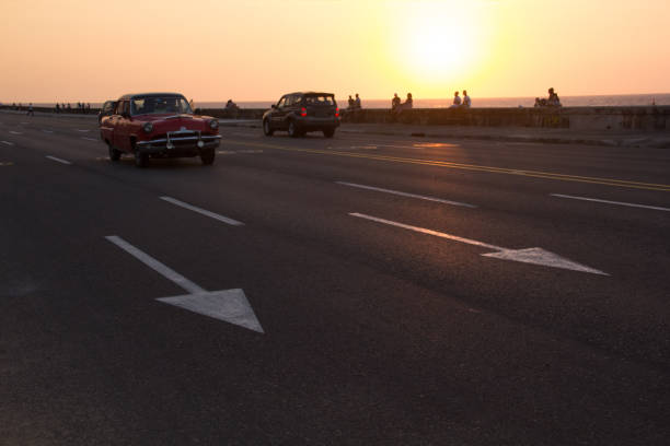 istock Classic red car driving on Cuban malecon during golden sunset 644066418