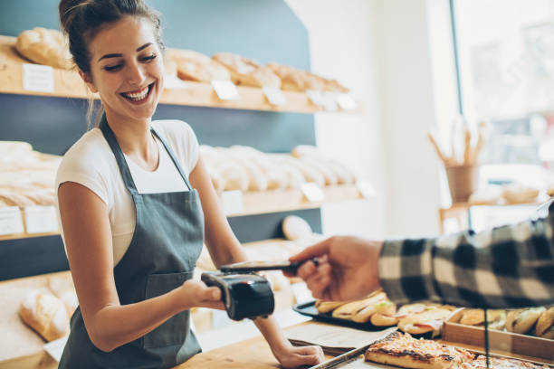 Contactless payment in the bakery Customer making a contactless payment with his phone in a bakery mobile payment stock pictures, royalty-free photos & images