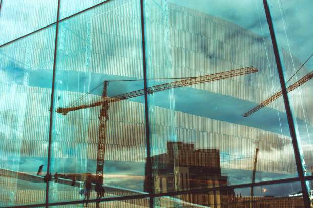istock Reflection of buildings and cranes, walking people in window 644086764