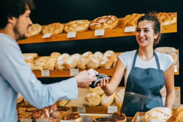 Young man making a contactless payment at a bakery