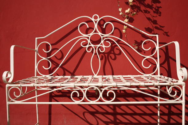 vintage design for a two seater in wrought iron, painted in white, in a sunny conservatory